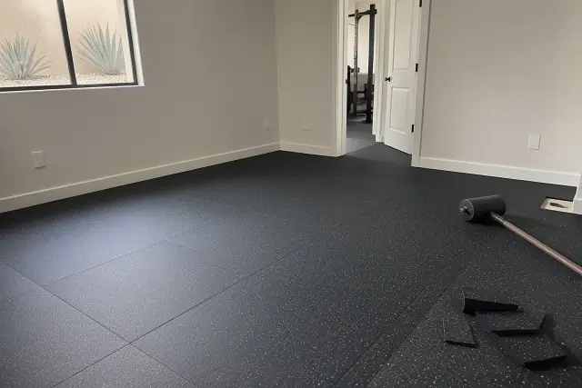 Rubber flooring installation in a residential basement in Glendale, AZ with visible floor seams and tools.