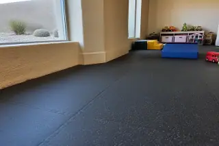 Interlocking rubber floor tiles installed in a basement playroom with desert landscaping visible in Phoenix, AZ.
