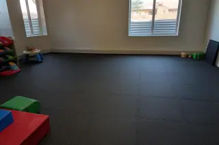 Interlocking rubber floor tiles installed in a basement in Phoenix, AZ, with children's foam blocks nearby.