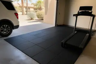 Interlocking rubber floor tiles installed in a home garage gym with Phoenix, AZ xeriscaped landscaping in the background.