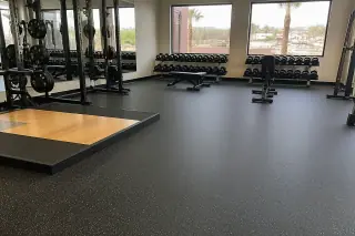 Black rubber flooring installed in a corporate gym with weight racks and desert views in Phoenix, AZ.