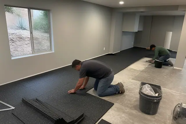 Contractors installing heavy-duty rubber flooring in a basement in Phoenix, AZ.