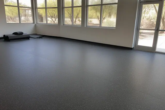 Newly installed rubber flooring in a school multipurpose room in Gilbert, AZ, with visible seams and exterior views.