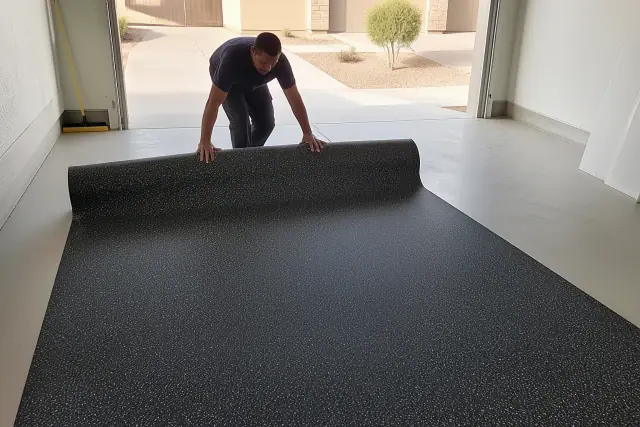 Worker unrolling recycled rubber flooring on a concrete garage floor in Goodyear, AZ.