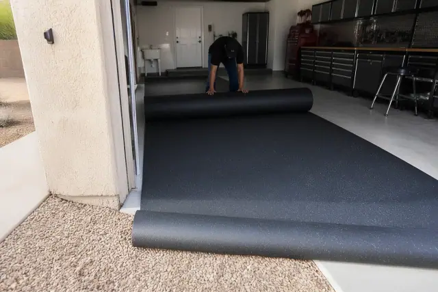 Worker installing recycled rubber flooring in a residential garage workshop in Mesa, AZ.