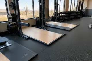 High-density rubber flooring seams under dumbbell racks in a corporate gym with desert and saguaro cacti in Phoenix, AZ.