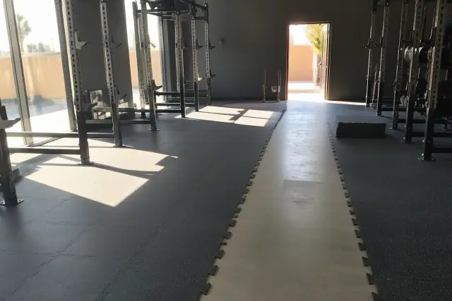Interlocking rubber floor tiles installed around squat racks in a fitness center in Phoenix, AZ.
