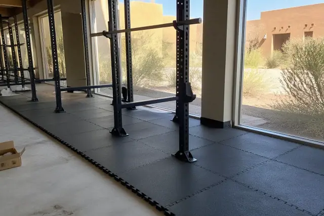 Interlocking rubber gym tiles installed around a squat rack in a fitness center in Phoenix, AZ.