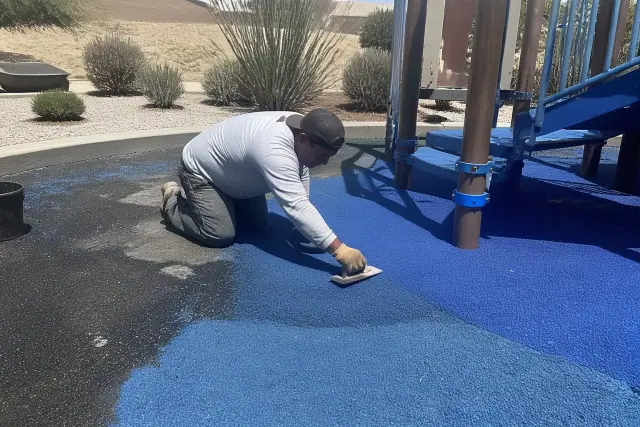 Technician repairing rubber playground flooring with granules and binder in Phoenix, AZ.