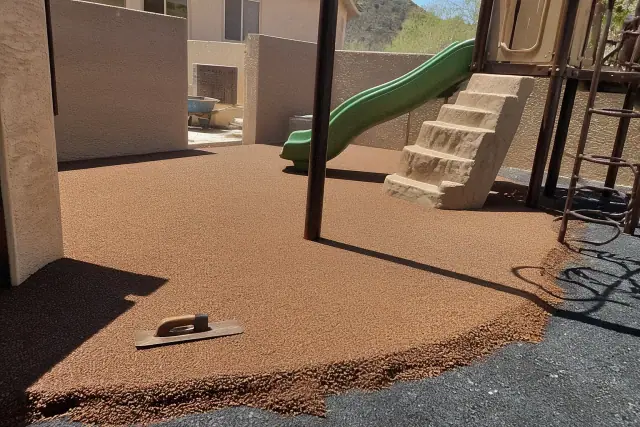 Technician troweling poured-in-place rubber surfacing around playground equipment in Phoenix, AZ.