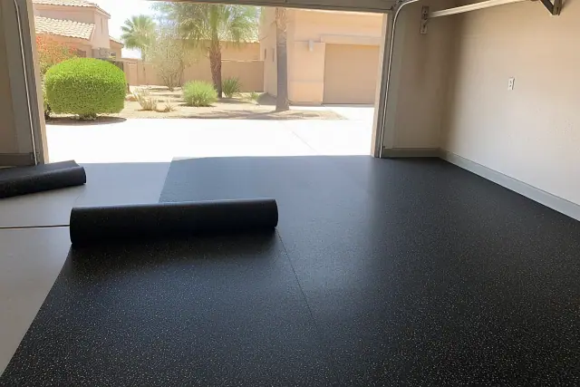 A contractor unrolling recycled rubber flooring on a concrete garage floor in Surprise, AZ.