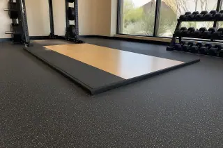 Rolled rubber flooring beneath weight racks in a corporate gym with desert views in Phoenix, AZ.
