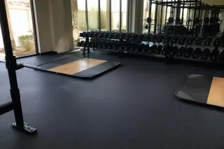 Rolled rubber flooring beneath weight racks in a Phoenix, AZ corporate gym.