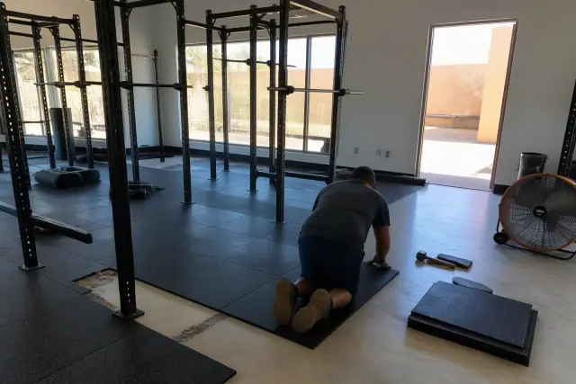Technician installing heavy-duty rubber floor tiles in a gym in Glendale, AZ.