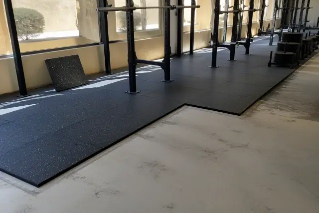 Technician installing rubber floor tiles in a fitness center free weight zone in Phoenix, AZ.