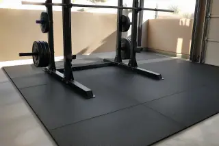 Impact-absorbing rubber gym mats installed under a barbell squat rack in Phoenix, AZ.
