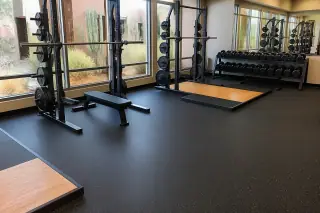 High-density rolled rubber flooring installed under gym equipment with saguaro cacti visible in Phoenix, AZ.