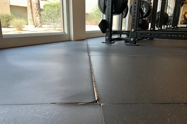 Worn gym flooring with curling edges and high-traffic paths in a fitness center in Phoenix, AZ.