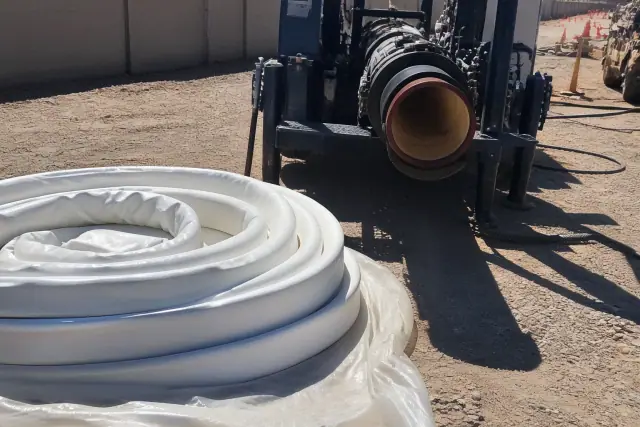 Resin-coated flexible pipe liner coiled next to a hydraulic inversion machine at a job site in Phoenix, AZ.