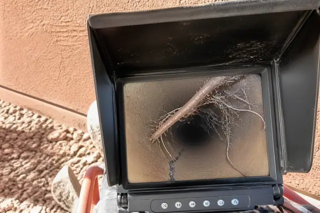 Sewer camera monitor showing pipe cracks and root intrusion during an inspection in Phoenix, AZ.