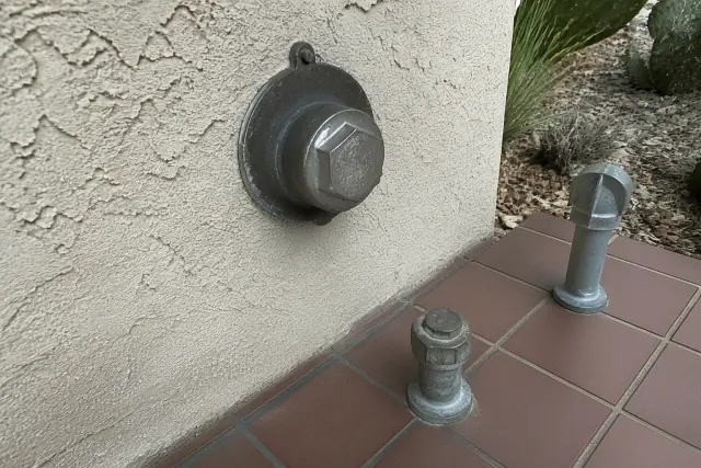 Metal sewer cleanout access pipe with a rugged cap on a stucco wall at a commercial site in Phoenix, AZ.