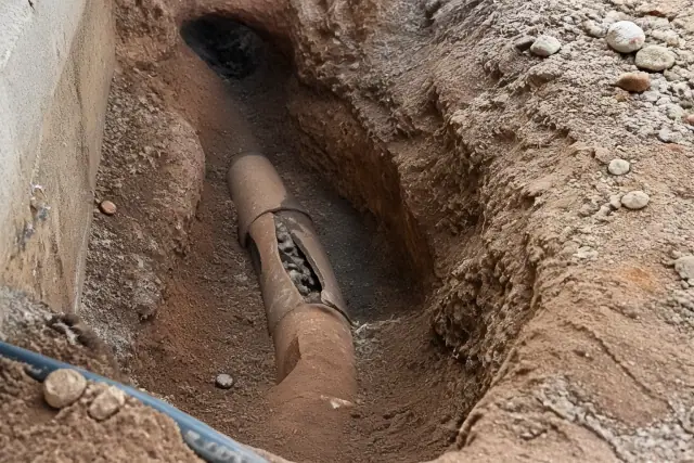Deep trench showing a cracked terra cotta sewer pipe in desert soil at a jobsite in Phoenix, AZ.