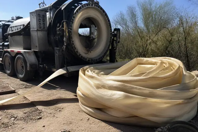 Resin-coated sewer liner coiled next to a hydraulic inversion machine at a trenchless repair site in Phoenix, AZ.