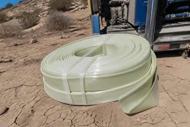 Resin-coated flexible liner material for sewer pipe repair coiled on the cracked desert soil in Phoenix, AZ.