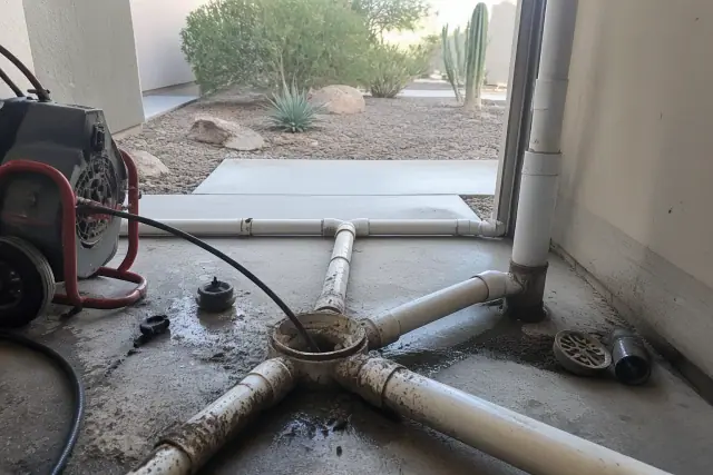 A professional auger snake clearing sewer pipes in a utility room basement in Gilbert, AZ.