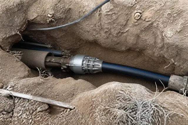 Hydraulic bursting head pulling HDPE pipe through an entry pit at a sewer installation jobsite in Phoenix, AZ.