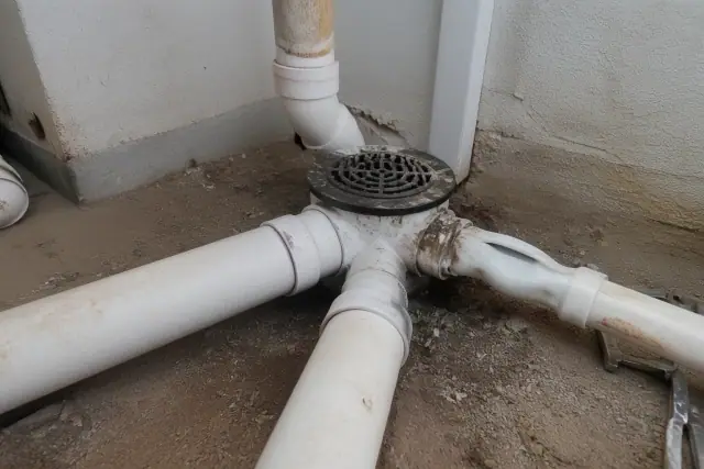 Heat-damaged and warped PVC drainage pipes on a utility room floor in Phoenix, AZ.