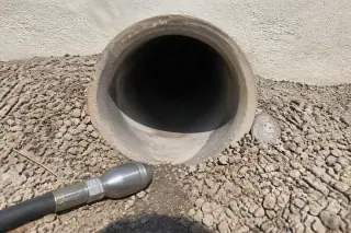 Cleaned drainage pipe opening surrounded by desert gravel at a worksite in Phoenix, AZ.