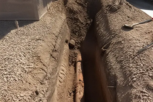 Deep trench with exposed cracked terra cotta sewer pipe and soil during a repair project in Phoenix, AZ.