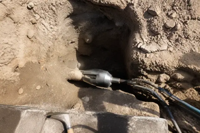 Pneumatic pipe bursting equipment in an entry pit at a sewer repair jobsite in Phoenix, AZ.
