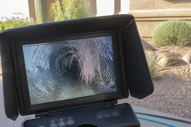 Sewer camera monitor showing tree roots and pipe obstructions during an inspection in Phoenix, AZ.