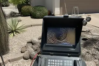 Sewer inspection monitor showing pipe conditions and tree roots in a Phoenix, AZ yard.