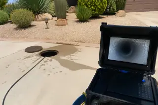Portable sewer camera console on a concrete driveway in Phoenix, AZ, displaying a clear pipe inspection.
