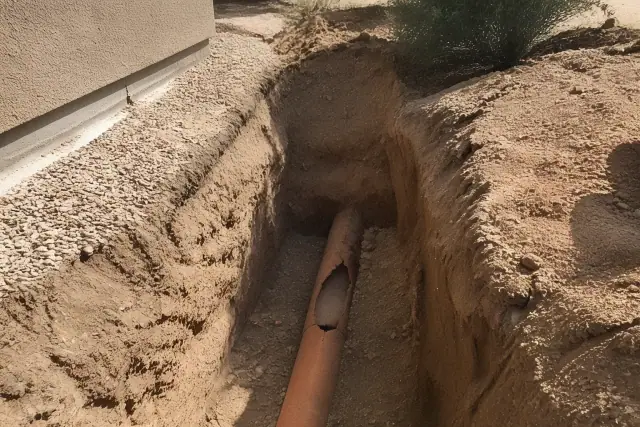 A trench excavation revealing a cracked terra cotta pipe at a sewer line repair job site in Surprise, AZ.
