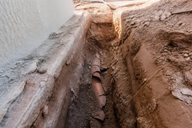 Deep trench excavation for a sewer line repair revealing cracked pipe in Phoenix, AZ.