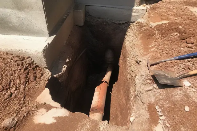 A deep trench in Mesa, AZ showing a cracked terra cotta sewer pipe during a foundation excavation and repair.