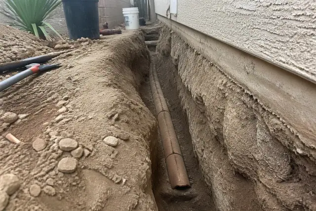 Deep trench with cracked terra cotta piping and exposed soil during a sewer line replacement in Avondale, AZ.