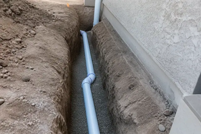 New PVC sewer pipe installed in a gravel trench during a home foundation excavation in Mesa, AZ.