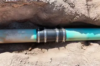 Underground pipe coupling with rubberized gaskets and desert gravel at a sewer repair site in Phoenix, AZ.