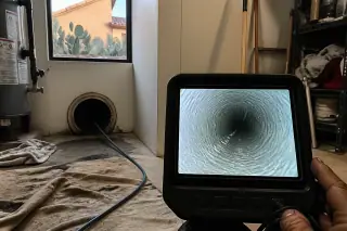 Cured resin liner texture inside a sewer pipe with a view of a Phoenix, AZ utility room window and prickly pear cactus.