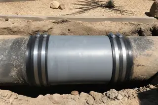 Underground pipe coupling with heavy-duty rubber gaskets near desert landscaping in Phoenix, AZ.
