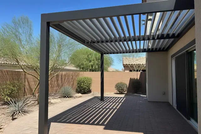 Adjustable metal louvered patio roof installed over a paved residential backyard in Phoenix, AZ.