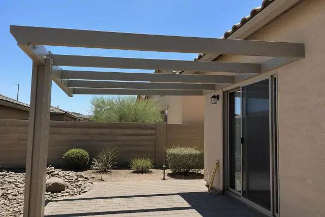 Partially installed aluminum patio cover with rafters and a level at a jobsite in Phoenix, AZ.