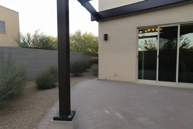 Cantilever shade structure with steel base bolted to stone pavers at a building site in Goodyear, AZ.