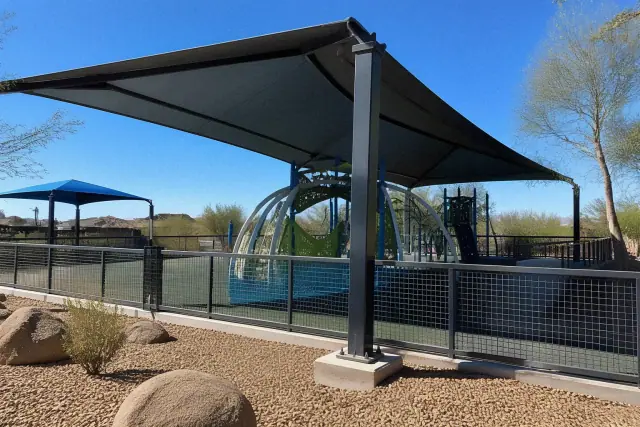 Cantilever shade structure over playground climbing equipment in a Phoenix, AZ park with concrete footings.