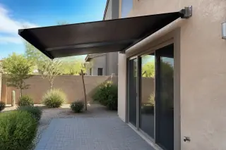 Cantilever shade structure mounted to a stucco wall over a stone patio in a Phoenix, AZ backyard.